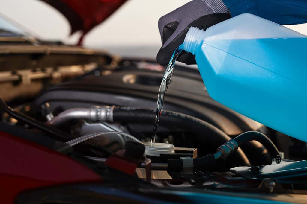 Mazda service technician filling windshield wiper fluid