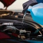 Mazda service technician filling windshield wiper fluid