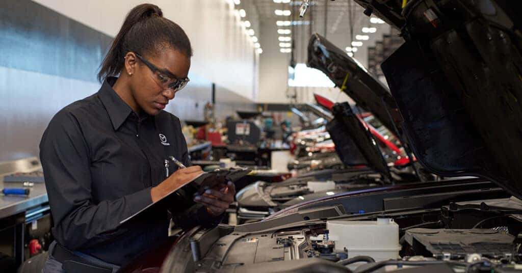 Technician inspecting a vehicle at a Mazda service center