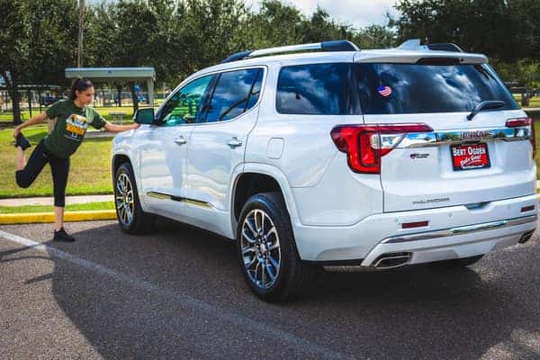 Female stretching next to 2020 GMC Acadia