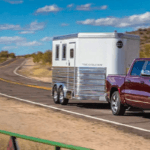 2019 RAM 1500 towing a trailer down a small hill on a paved road.