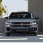 Gray 2026 Volkswagen Jetta GLI sedan parked in a modern concrete structure, front view.