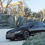 A black 2022 Volkswagen Arteon is shown driving down a modern driverway.