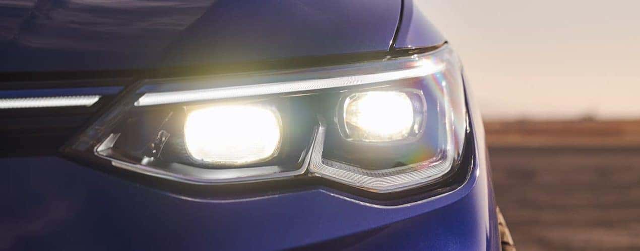 A close up shows the driver side headlight on a blue 2022 Volkswagen Golf R.