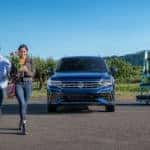 A blue 2022 Volkswagen Tiguan is shown parked at a garden center.