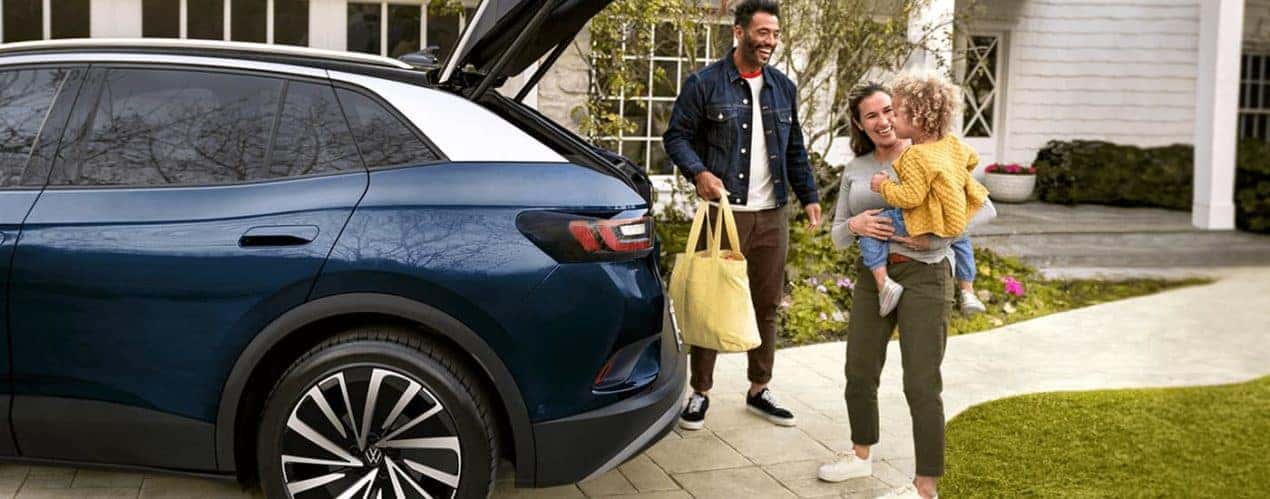A family is shown taking groceries out of a blue 2023 Volkswagen ID.4 Electric Vehicle.