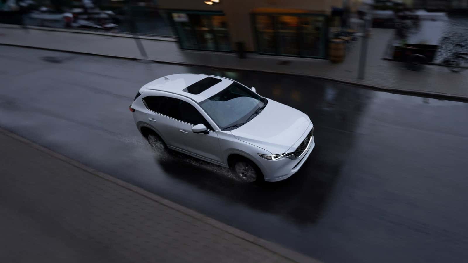 Overhead shot of a 2025 Mazda CX-5 driving down the road. The CX-5 is white in color.