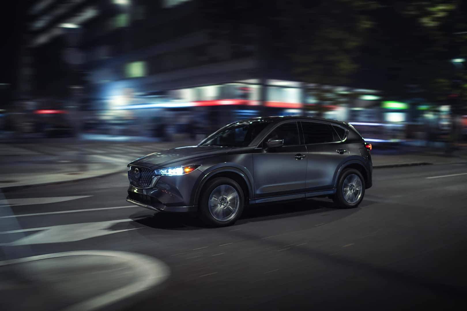 2024 Mazda CX-5 driving down the road at night.
