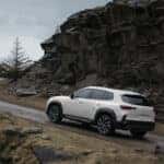 A white Mazda CX-50 driving up a hill
