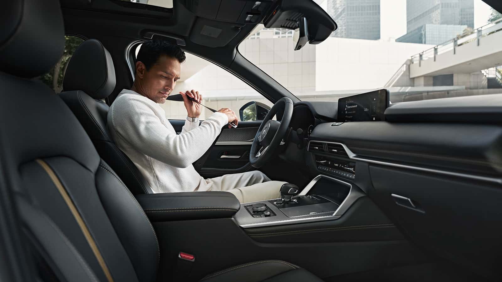 Driver putting his seatbelt on in a Mazda CX-70