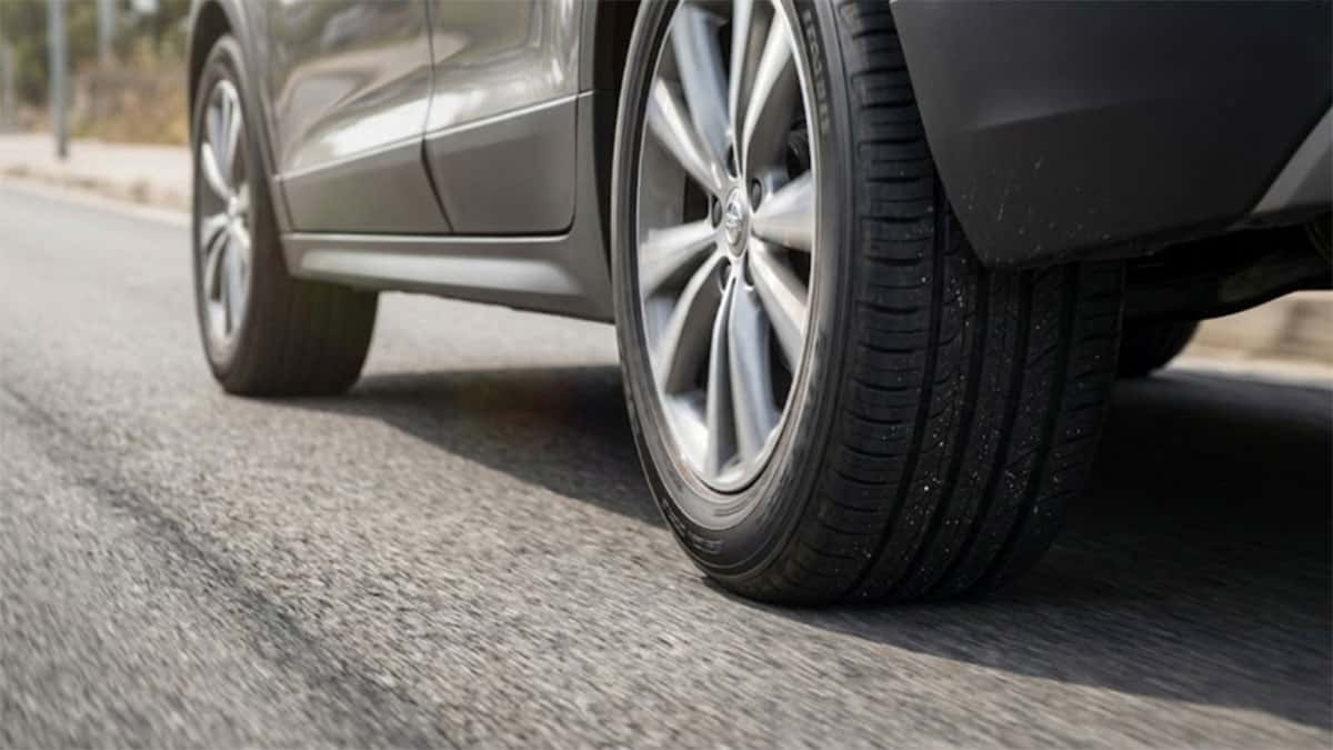 Close view of an SUV’s tire and alloy wheel rolling on an asphalt road