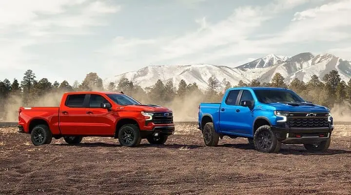 Two New Chevrolet Silverados in a dirt field.