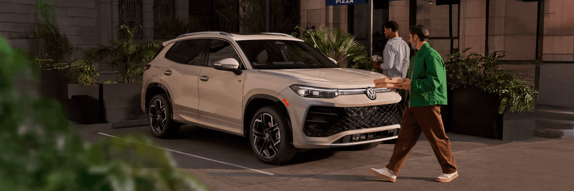 Two people outside a restaurant talking next to a white Volkswagen SUV