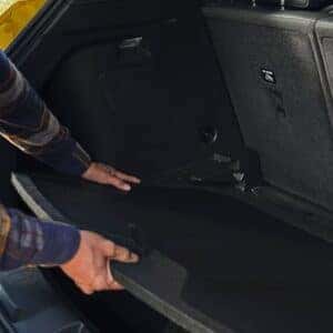 Close-up of a person adjusting the cargo floor in the 2025 Chevrolet Trailblazer, showcasing the versatile rear storage area with split-folding seats for added flexibility.