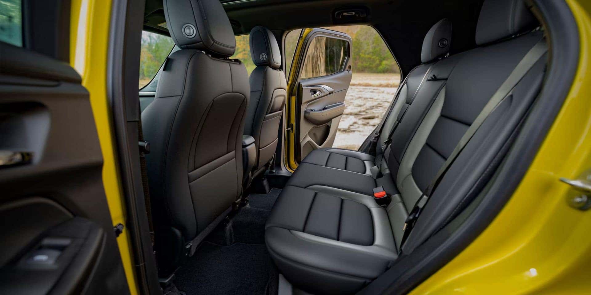 Rear seating area of the 2025 Chevrolet Trailblazer, showcasing spacious black leather seats with modern styling and an open rear door highlighting easy access.