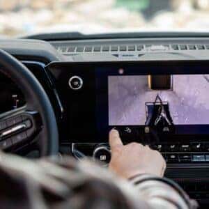 Driver using the infotainment system of the 2025 Chevrolet Colorado, displaying a trailer camera view.