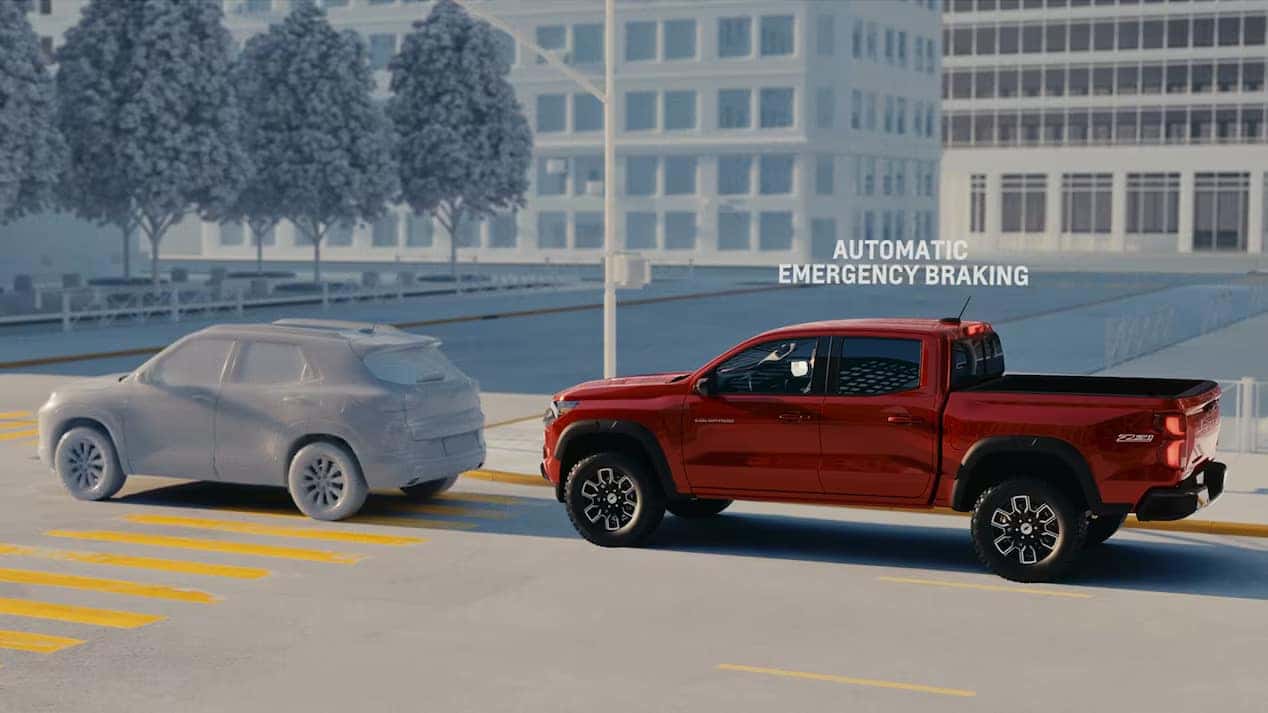 Red Chevrolet Colorado activating forward collision alert with an emergency braking indicator as it approaches another vehicle.