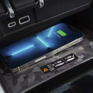 A smartphone charging wirelessly on a patterned surface within the center console of a modern pickup truck.