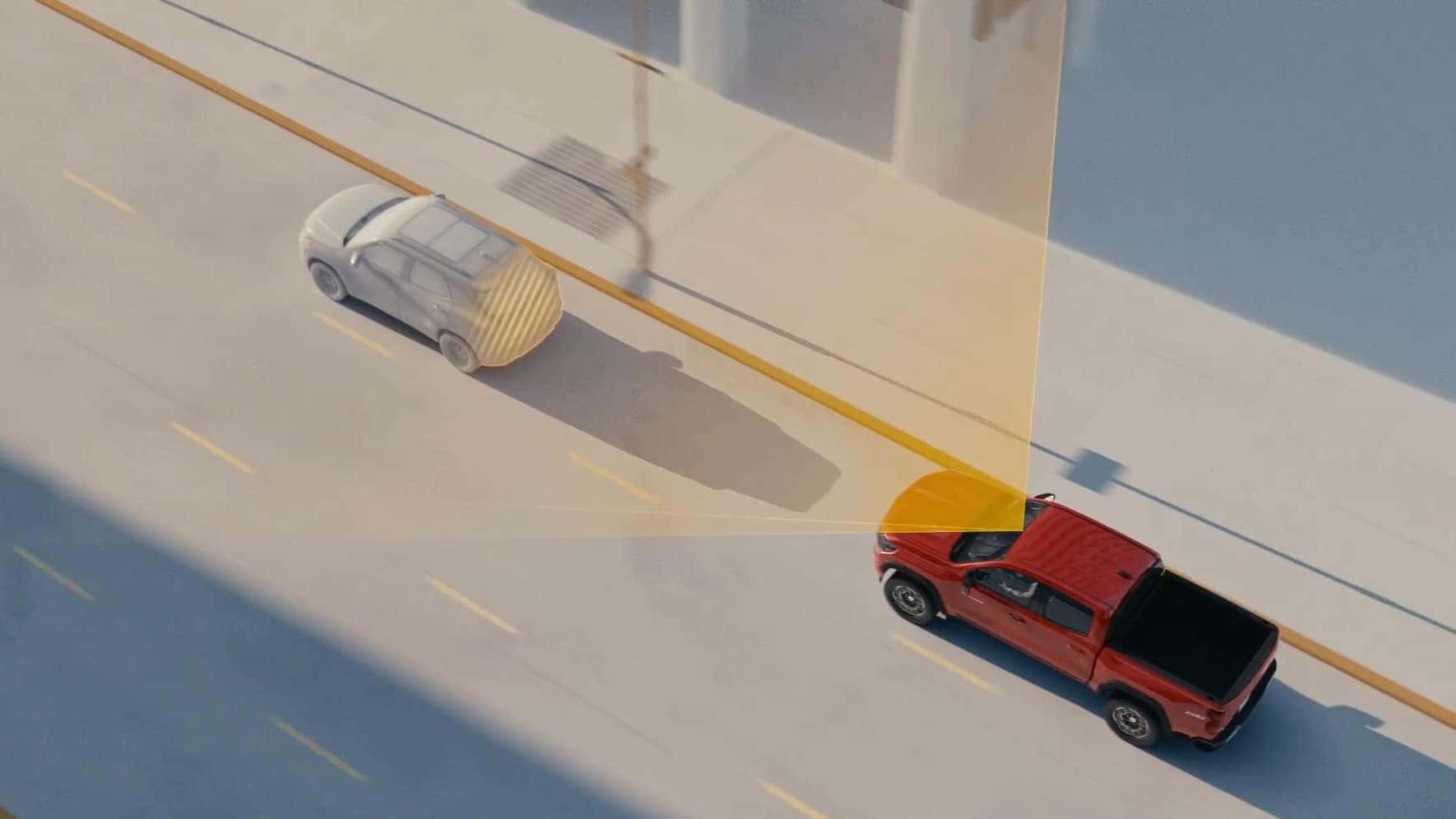 Red pickup truck demonstrating pedestrian detection safety technology on a city street with highlighted safety zones.