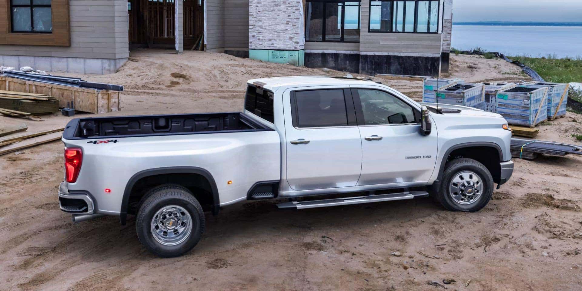 a white silverado hd 4x4 parked at a construction site next to a lake