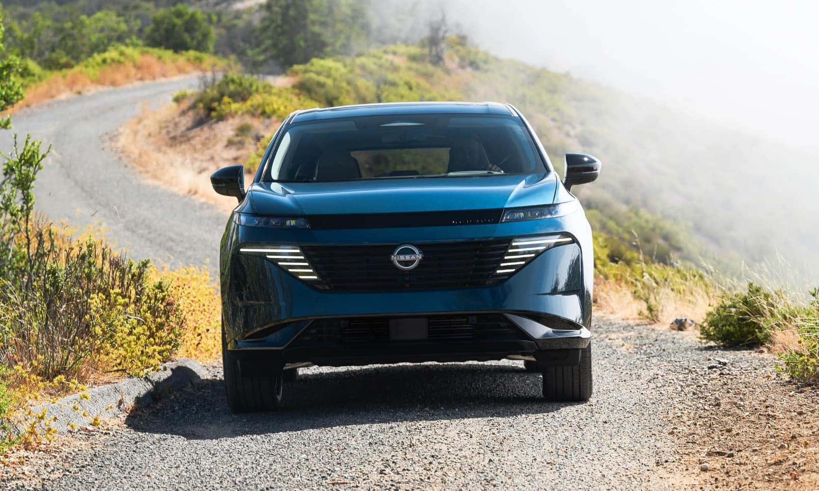 a blue 2025 Nissan Murano driving on a mountain-side rocky road into the camera lens
