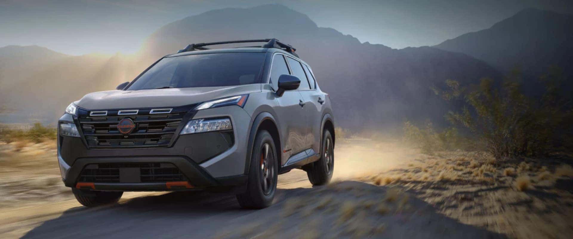 Hero image of a light brown 2025 Nissan Rogue driving through a mountainous field