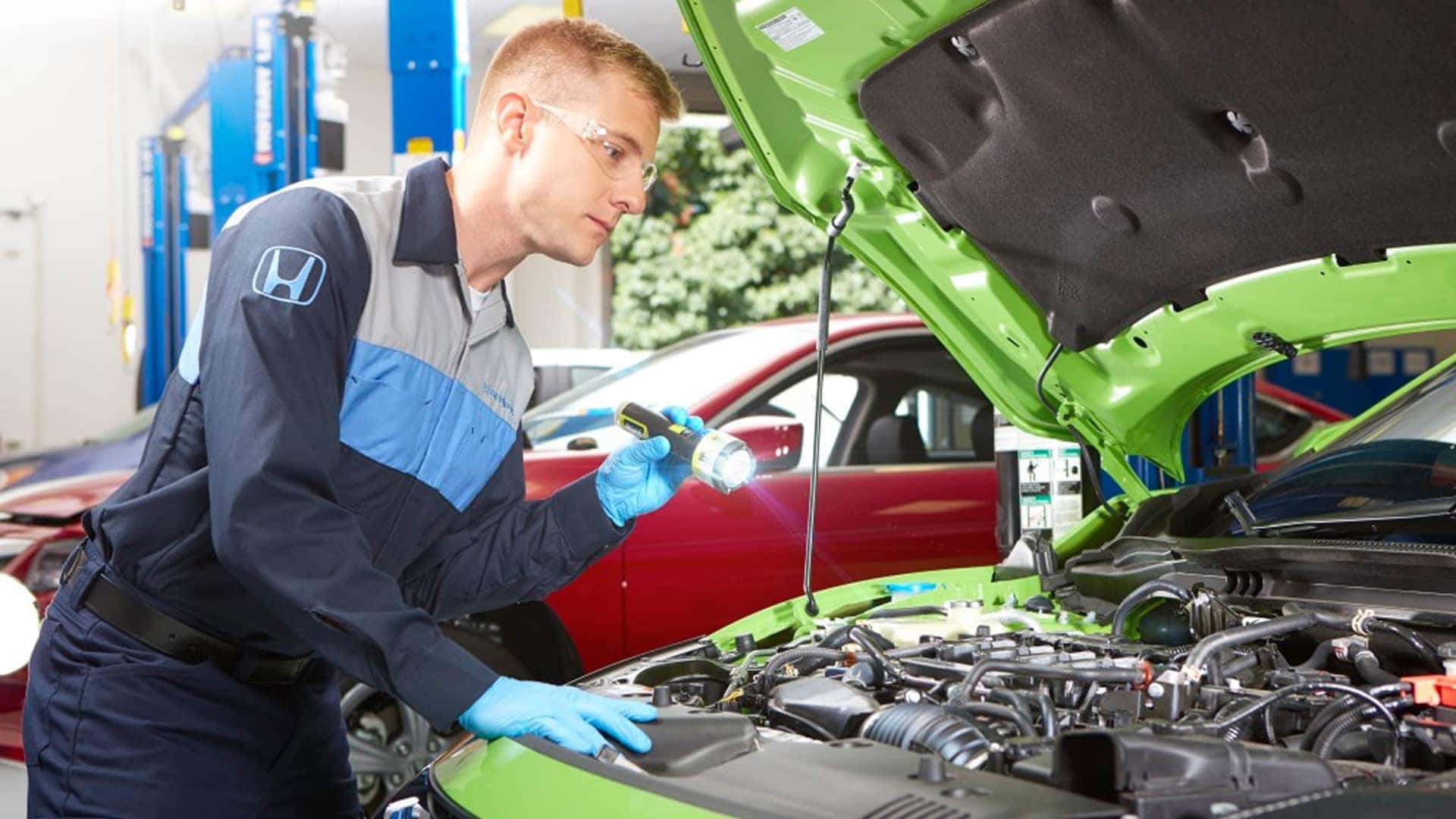 honda service technician working under hood of vehicle