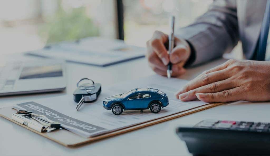 Consultant reviewing financing paperwork with keys on a desk