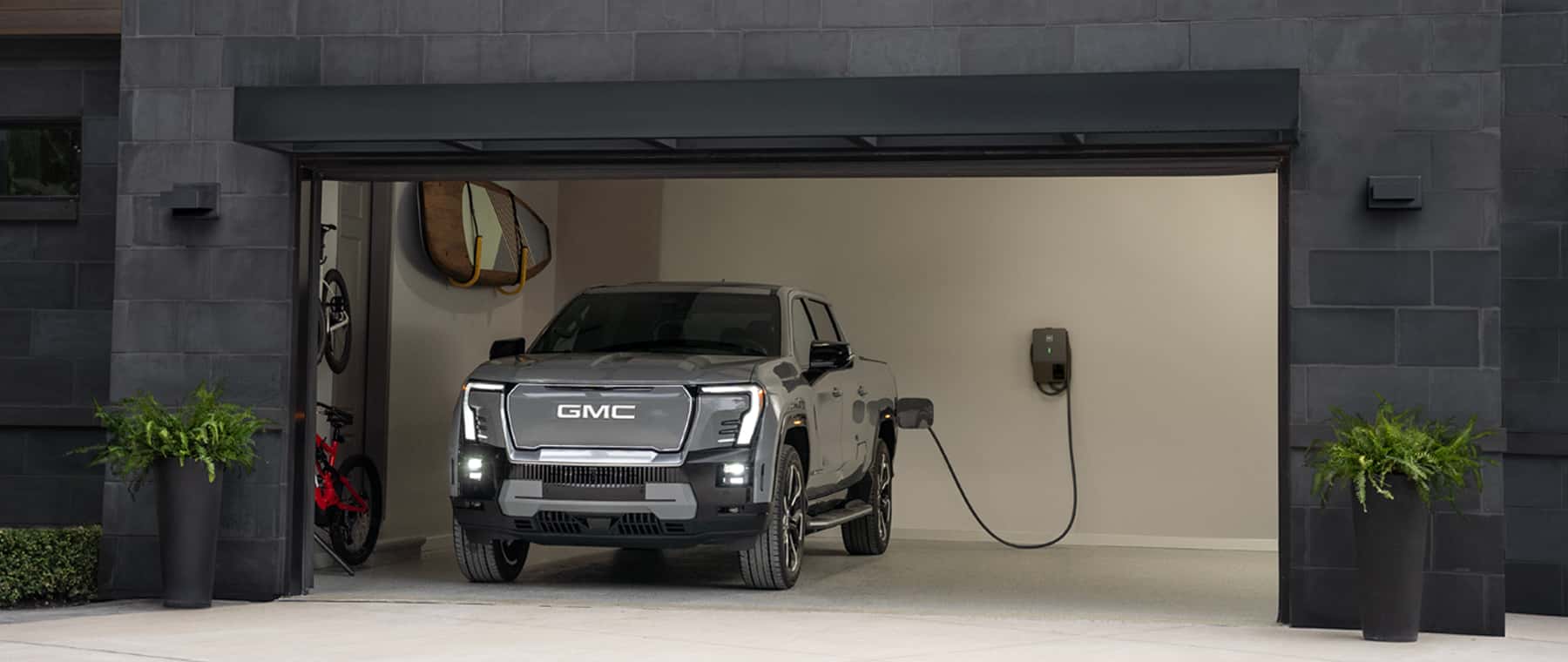 Electric GMC truck parked in garage and plugged in.