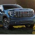 Front three-quarter view of a blue 2026 GMC Sierra 1500 pickup truck parked in a grassy field.