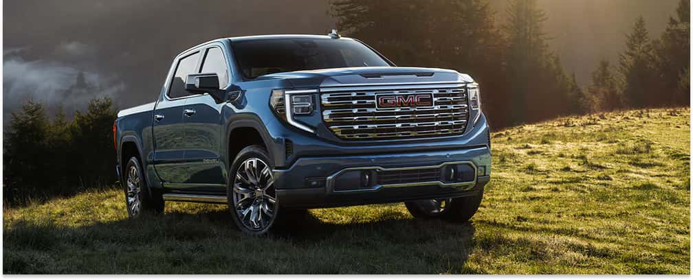 Front three-quarter view of a blue 2026 GMC Sierra 1500 pickup truck parked in a grassy field.