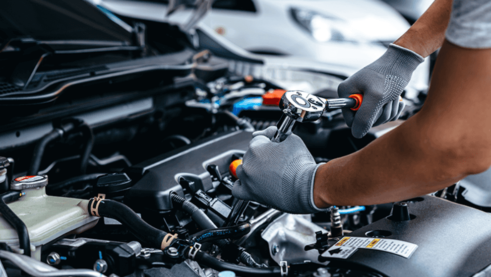 A mechanic is using a ratchet wrench to repair a car engine