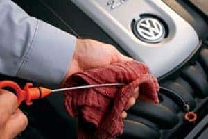 A VW technician checking the oil in a VW engine.
