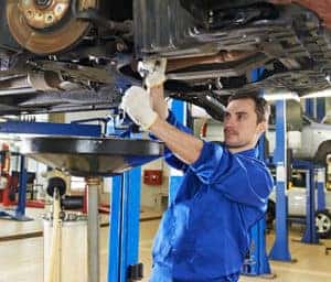 A VW technician working on the underside of a Volkswagen.