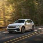 A white 2022 Tiguan SELR in Oryx White drives through a forest