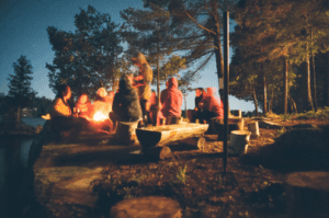Kids sitting around a nighttime campfire in a Marion, IL summer camp.