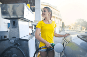 Woman in a yellow shirt fueling up her Volkswagen at a Marion, IL gas pump.