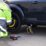 Man in a caution vest changing a Volkswagen tire in Marion, IL.