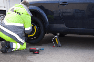 Man in a caution vest changing a Volkswagen tire in Marion, IL.