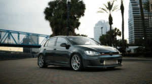 Volkswagen Golf in black paint parked in a tropical city parking lot.