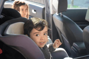 Two children sitting in their car seats inside a Volkswagen SUV.
